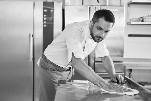 When preparing foods keep it clean, a dirty area should not be seen. Young male professional cook cleaning in commercial kitchen